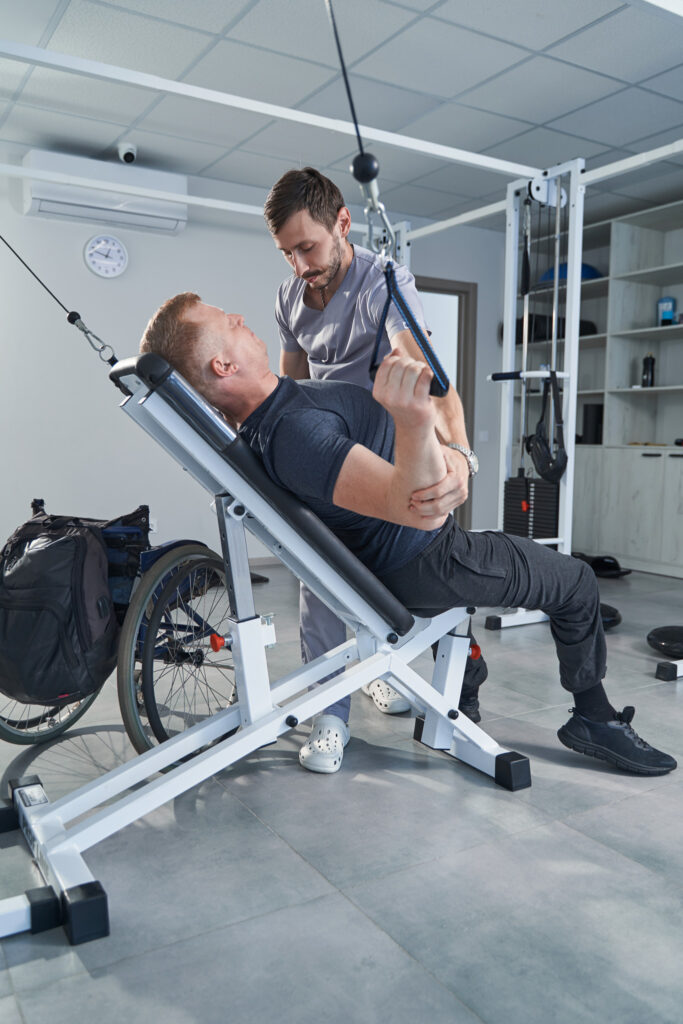 Man with disability stretches belt on strength-training machine